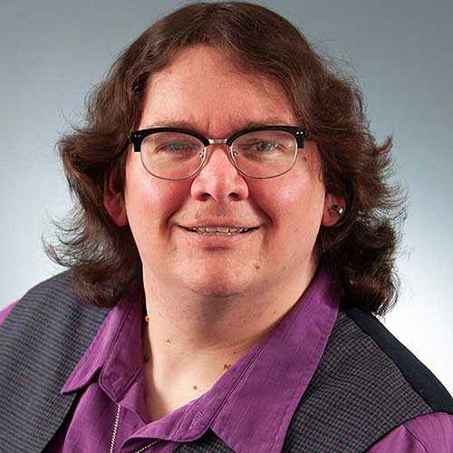 a close up of a person wearing a purple shirt and glasses