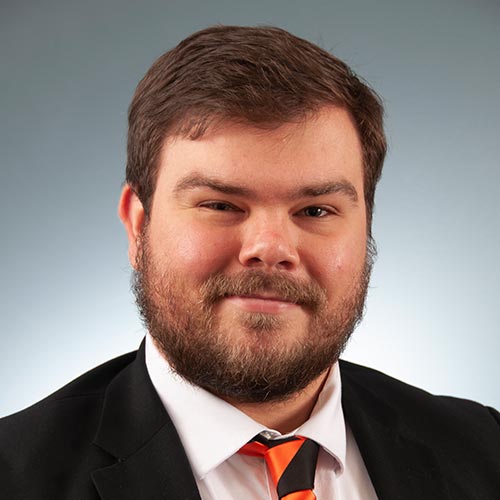 a man wearing a suit and tie smiling at the camera