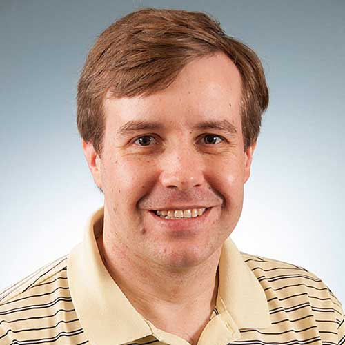 a man wearing a striped shirt and smiling at the camera