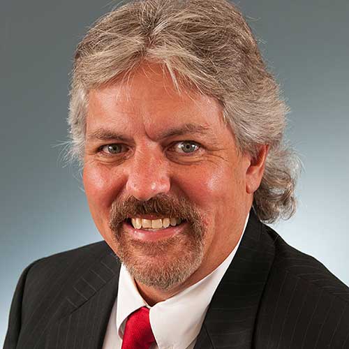 a man wearing a suit and tie smiling at the camera