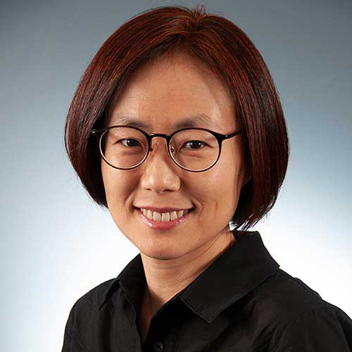 a woman wearing glasses and smiling at the camera