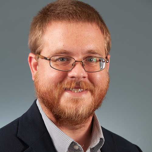 a man wearing glasses and smiling at the camera