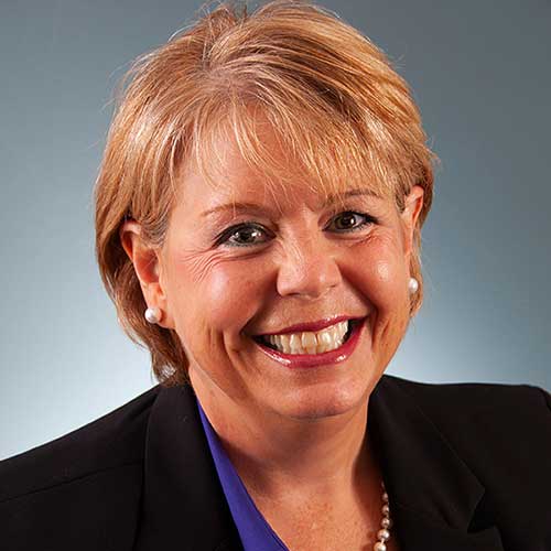 a person wearing a suit and tie smiling at the camera