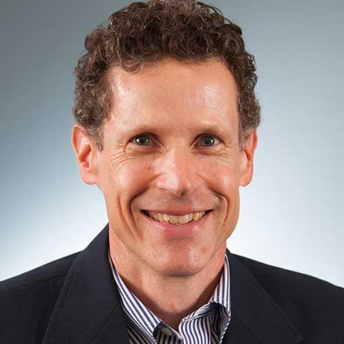 a man wearing a suit and tie smiling at the camera