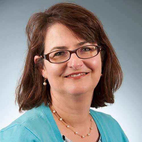 a woman wearing glasses and smiling at the camera