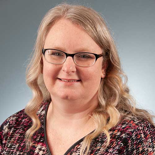 a woman wearing glasses and smiling at the camera