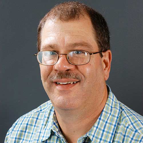 a man wearing glasses and smiling at the camera