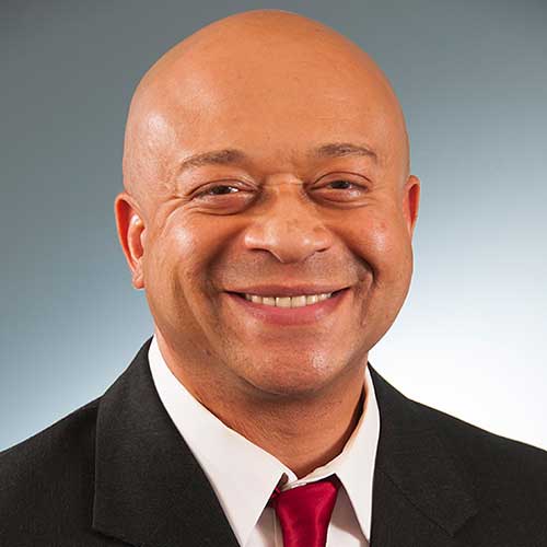 a man wearing a suit and tie smiling at the camera