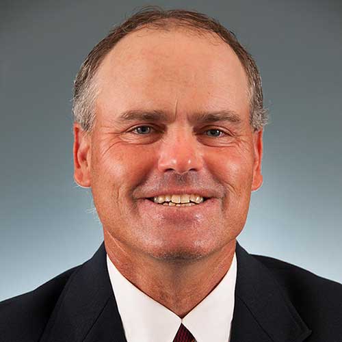 a man wearing a suit and tie smiling at the camera