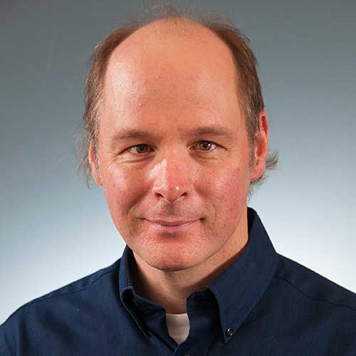 a man wearing a suit and tie smiling at the camera