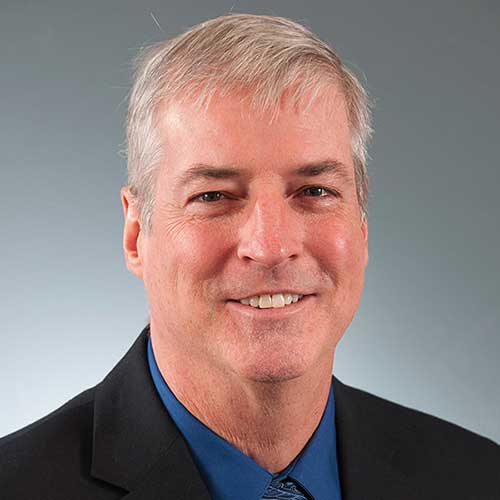 a man wearing a suit and tie smiling at the camera