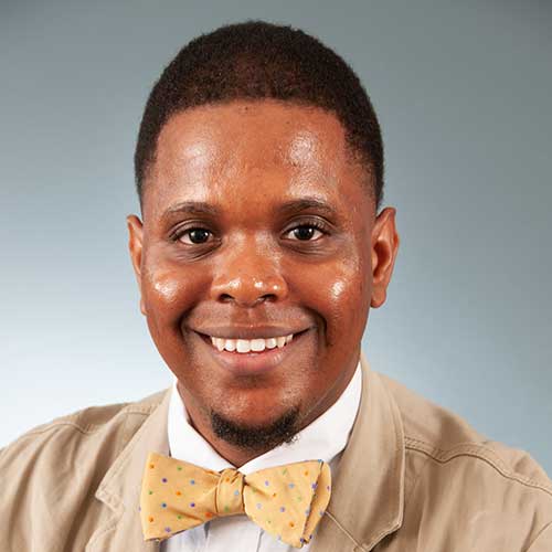 a man wearing a bow tie and smiling at the camera