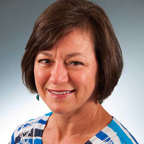 a woman wearing a blue shirt and smiling at the camera