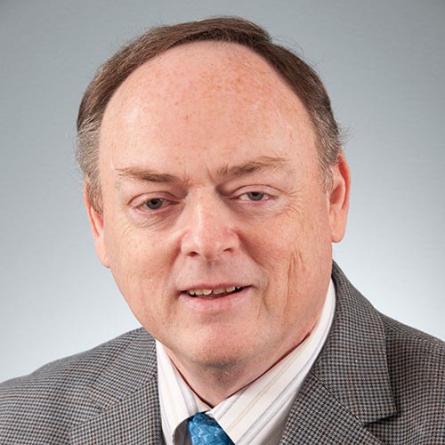 a man wearing a suit and tie smiling at the camera