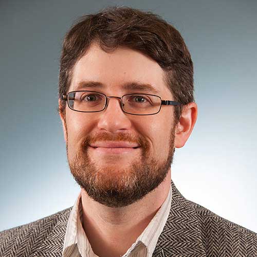 a man wearing glasses and smiling at the camera