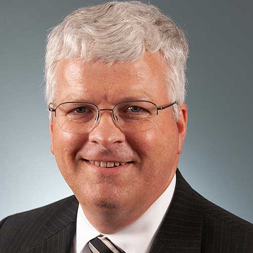 a man wearing a suit and tie smiling at the camera