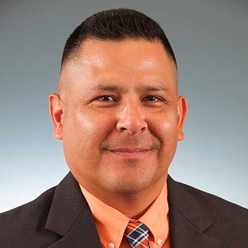 a man wearing a suit and tie smiling at the camera