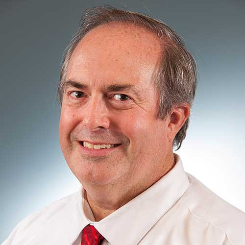 a man wearing a suit and tie smiling at the camera