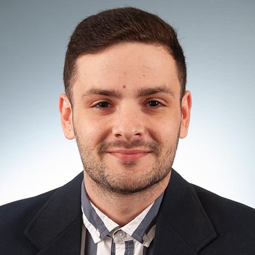 a man wearing a suit and tie smiling at the camera