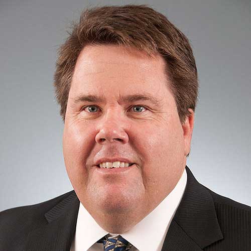 a man wearing a suit and tie smiling and looking at the camera