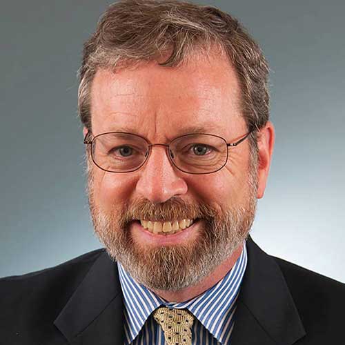 a man wearing a suit and tie smiling at the camera