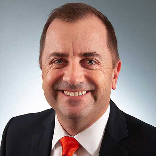 a man wearing a suit and tie smiling at the camera