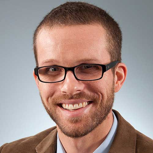 a man wearing glasses and smiling at the camera