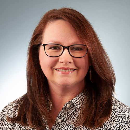 a woman wearing glasses and smiling at the camera