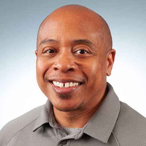 a man wearing a suit and tie smiling at the camera