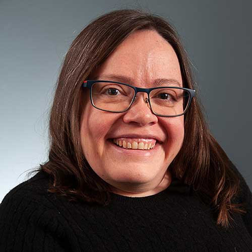 a woman wearing glasses and smiling at the camera