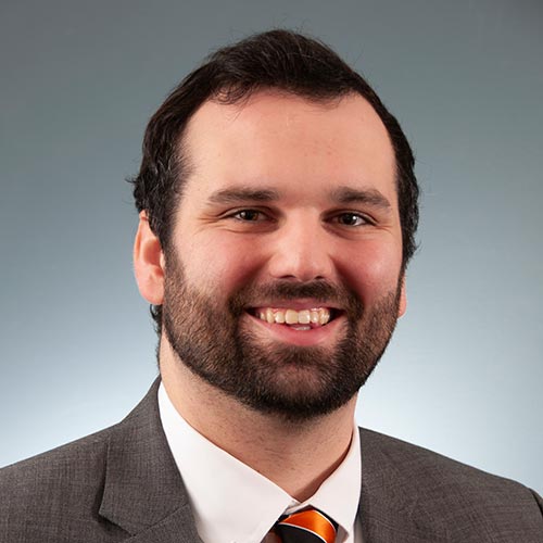 a man wearing a suit and tie smiling at the camera