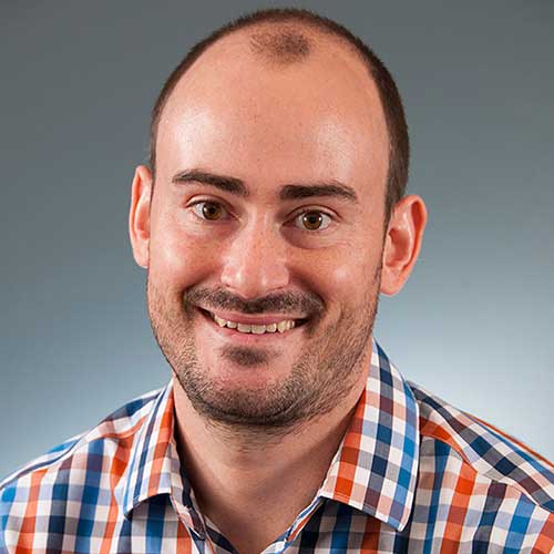 a man wearing a striped shirt and smiling at the camera