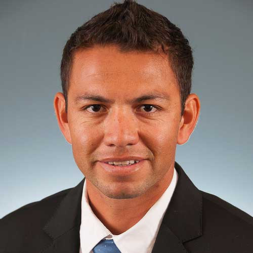a man wearing a suit and tie smiling at the camera