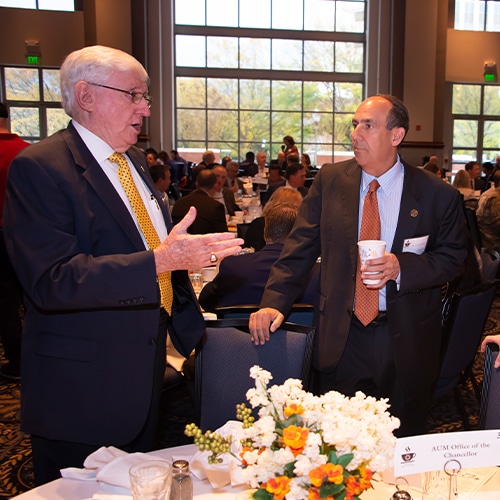 A Group Of People Standing Around A Table