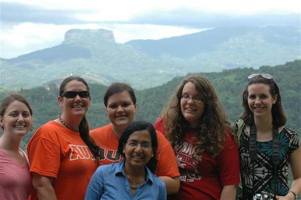Dola Banerjee et al. posing for a photo in front of a mountain