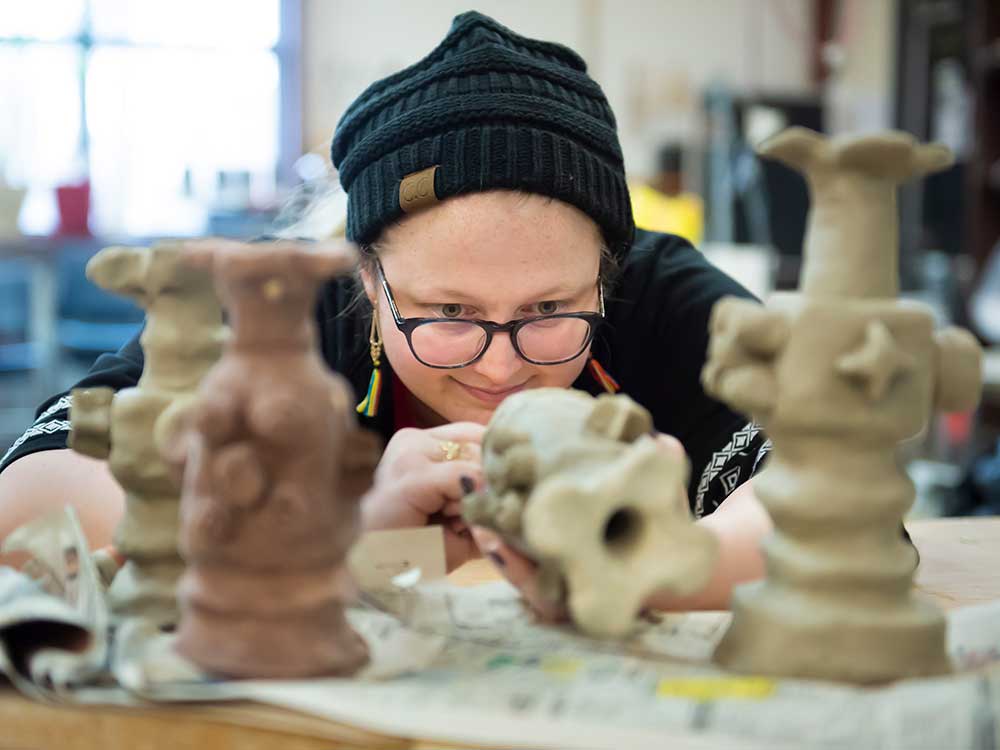 A young lady admiring her sculptures in class