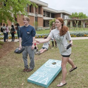 A Group Of People Playing Frisbee In A Yard