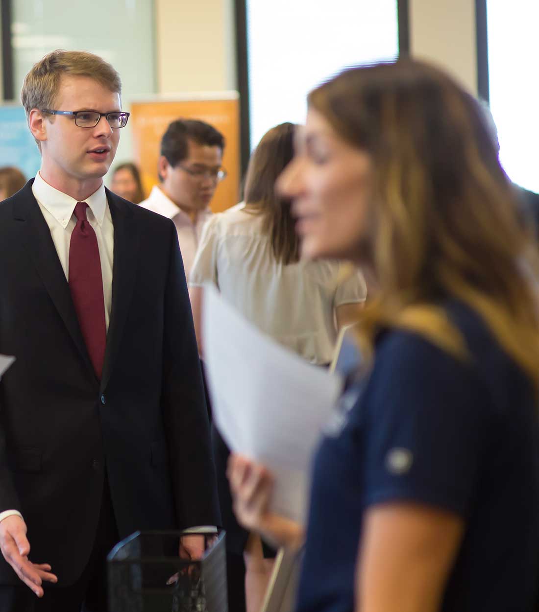 a group of people standing next to a man in a suit and tie