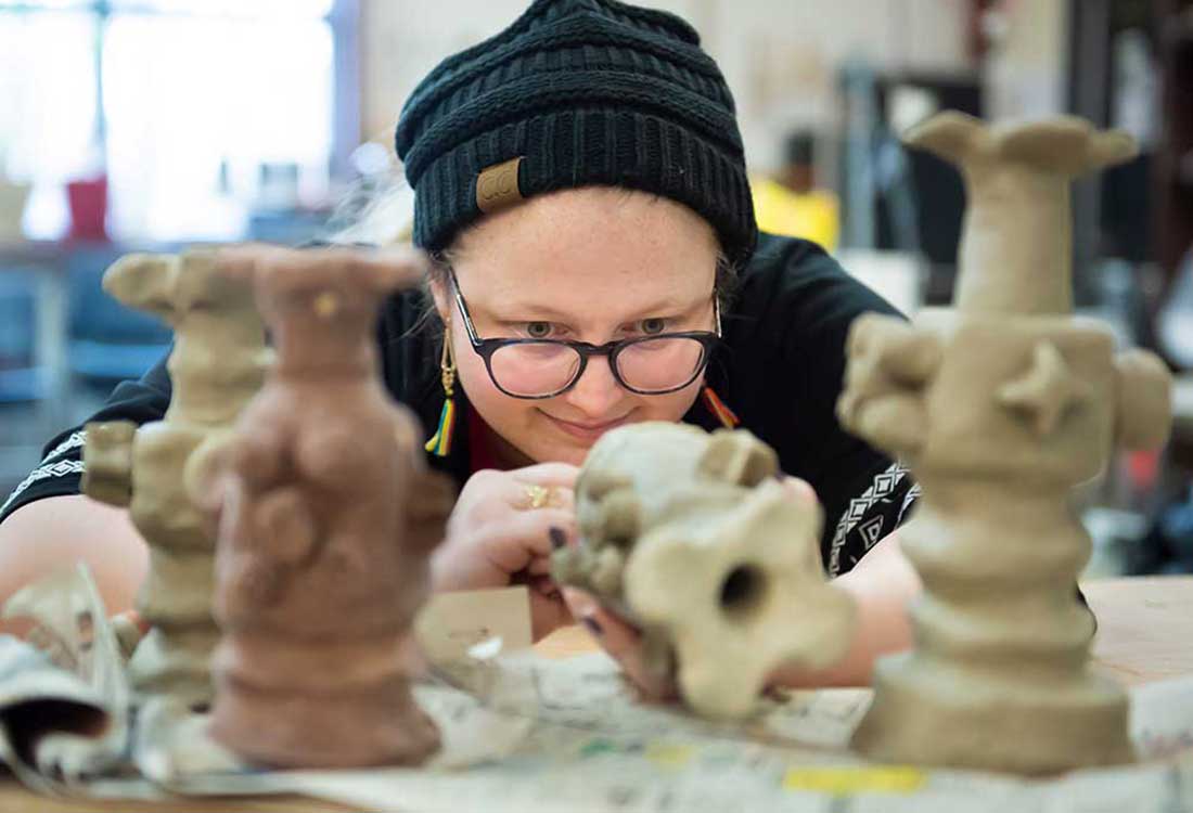 Auburn University at Montgomery art student crafting clay sculptures in ceramics studio