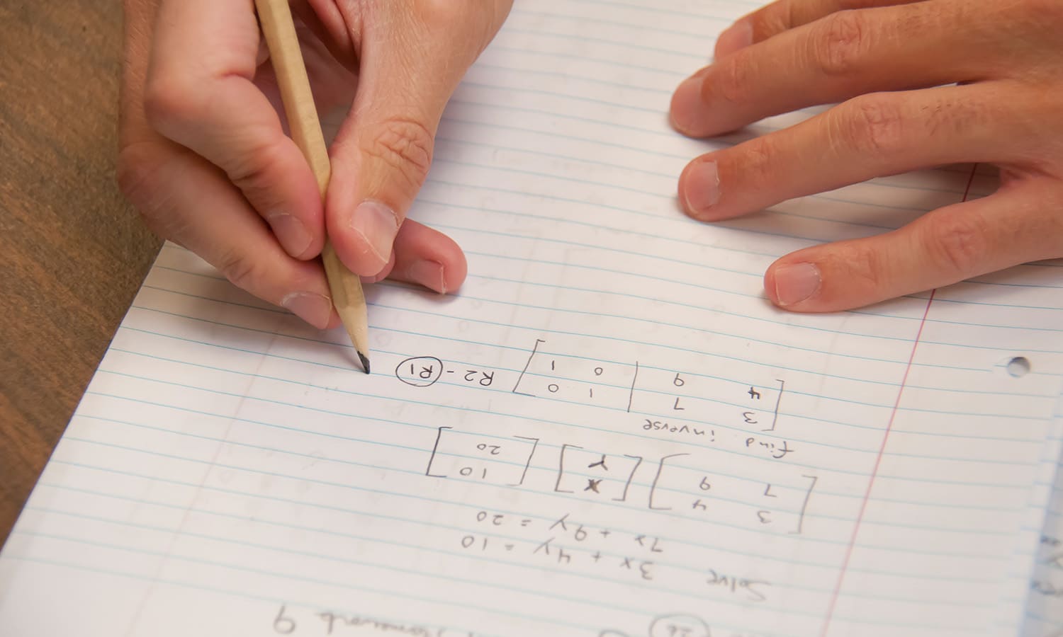 student writing math equations on notebook