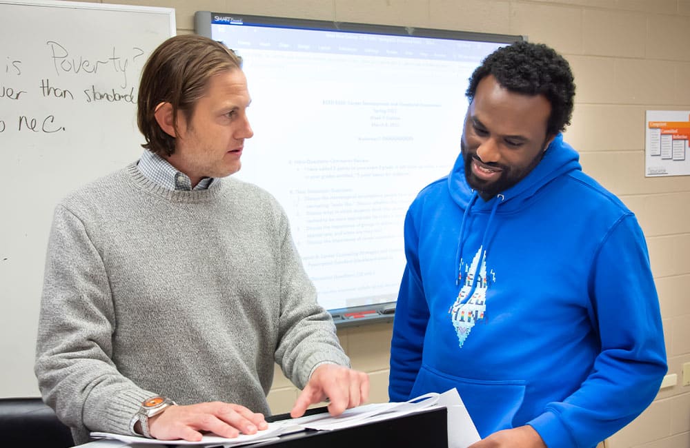 a man and a woman standing in front of a laptop