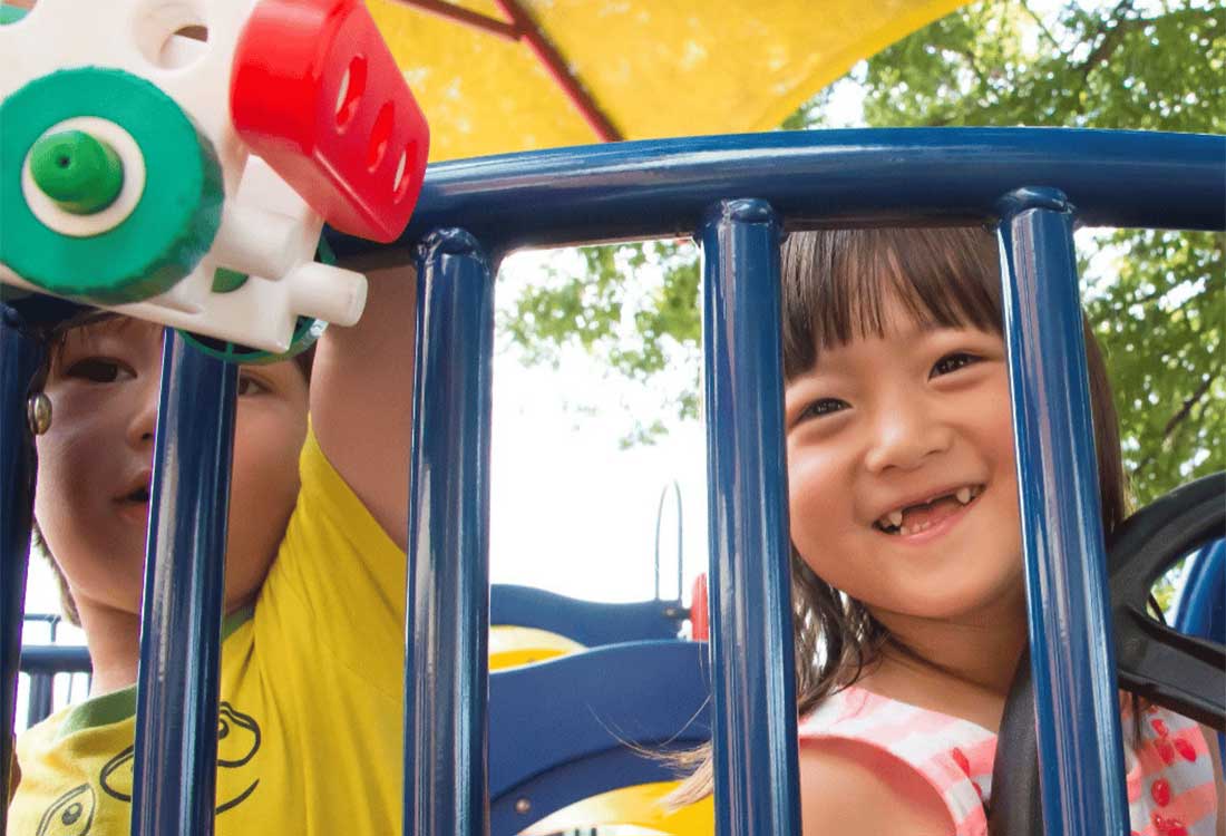Children smiling and playing on a blue playground at Auburn University at Montgomery campus