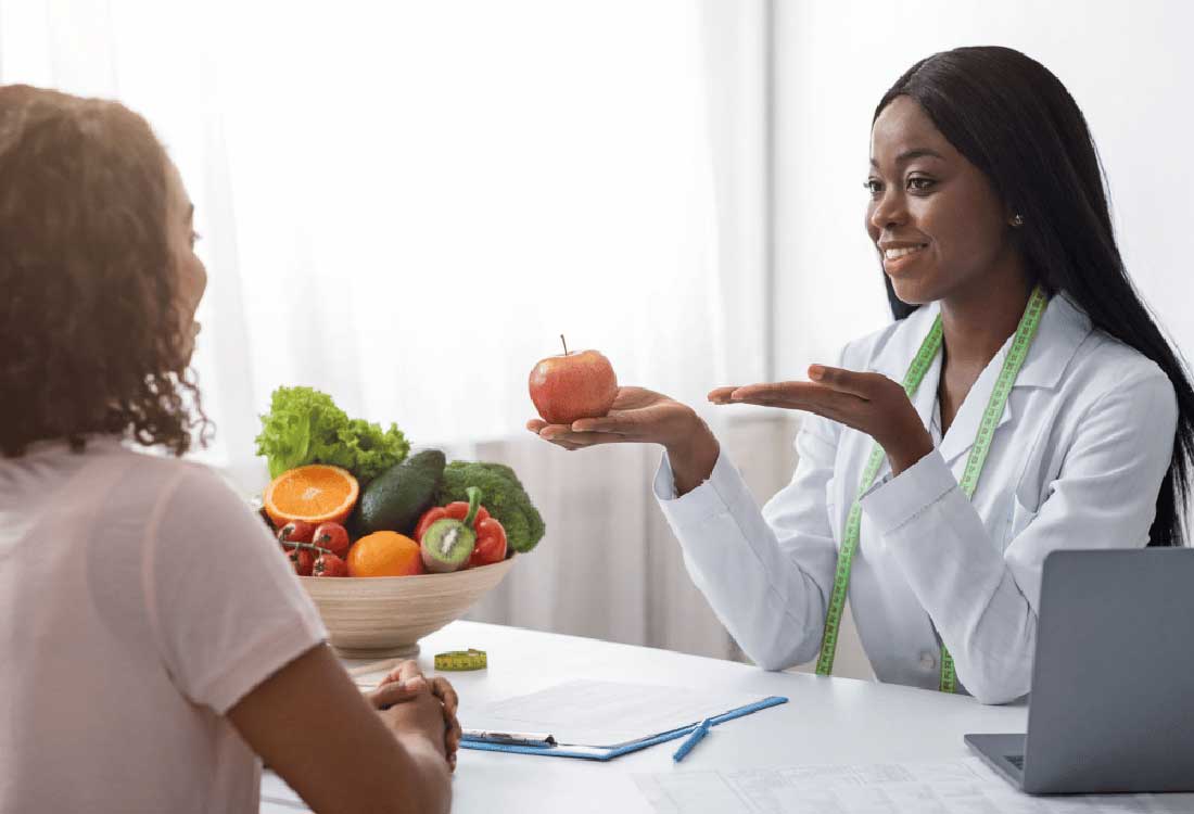 Auburn University at Montgomery nutrition counseling: a dietitian holds an apple while advising a student on healthy eating
