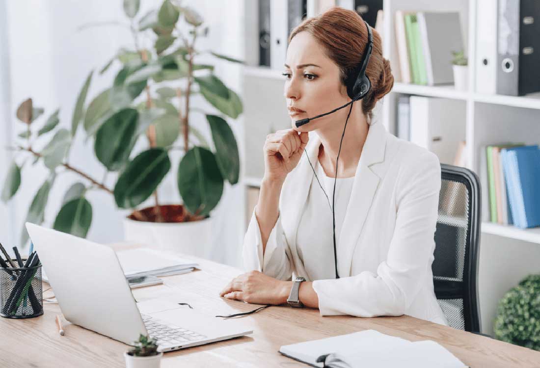 Auburn University at Montgomery advisor wearing a headset assists online students at a laptop