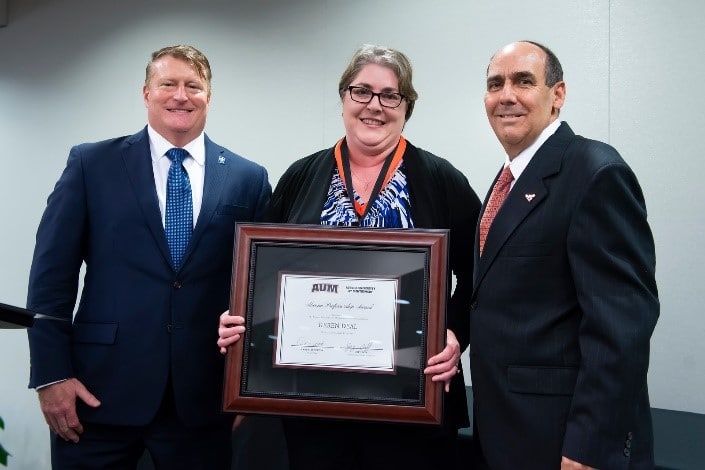 Elizabeth Frazee et al. standing next to a person in a suit and tie