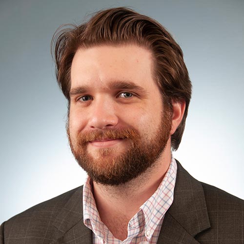 a man wearing a suit and tie smiling and looking at the camera