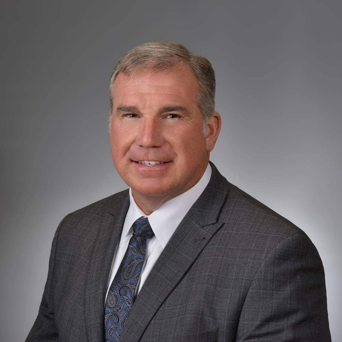 Randy Wilkes wearing a suit and tie smiling at the camera