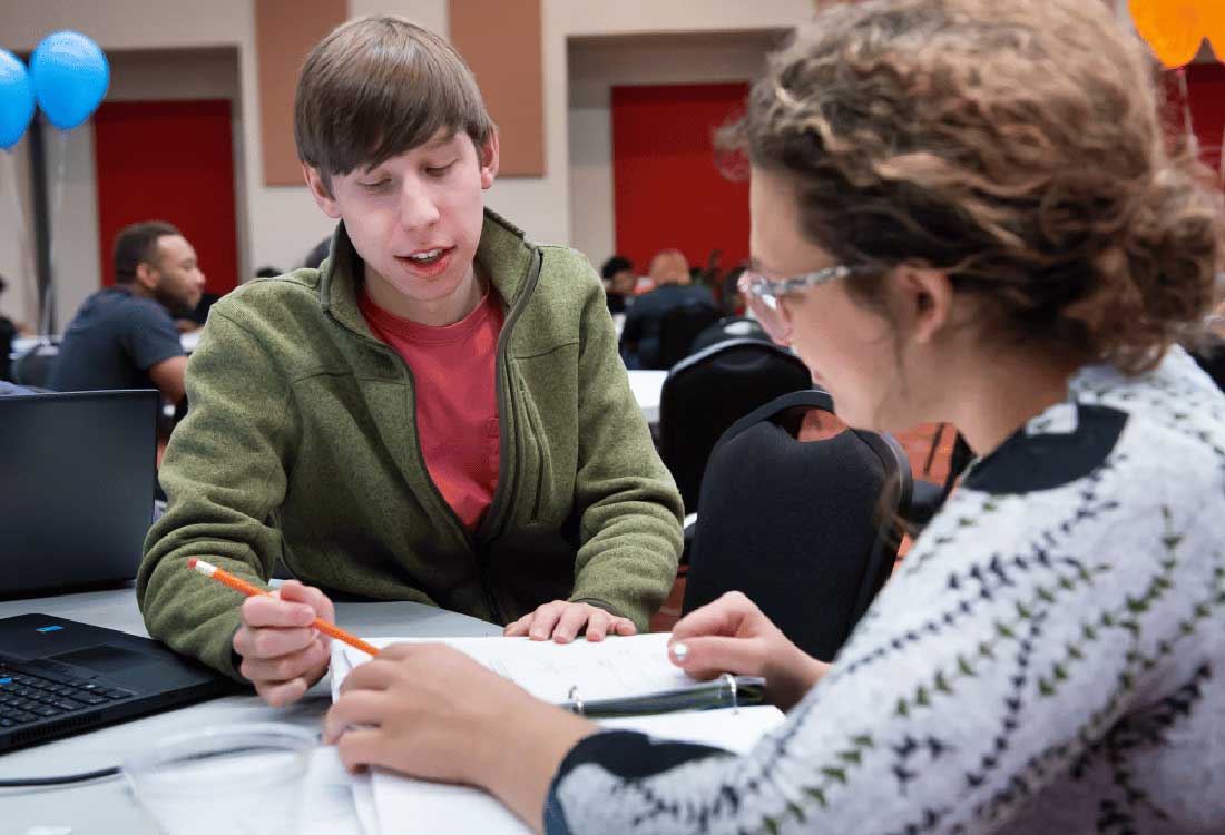 Auburn University at Montgomery students collaborate on homework at a campus tutoring session with notes and a laptop.