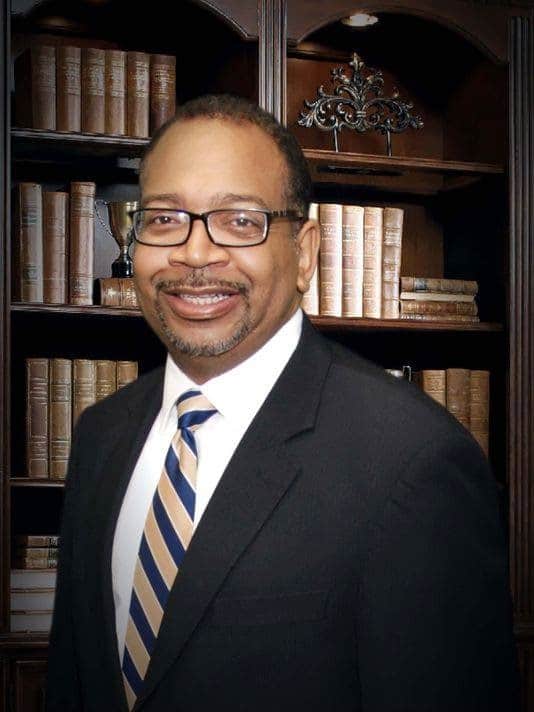 a man wearing a suit and tie smiling at the camera