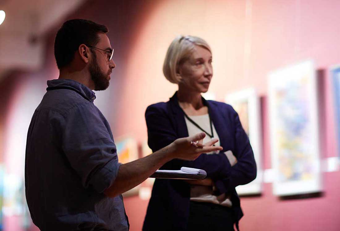 Two people discuss artwork at Auburn University at Montgomery campus gallery exhibition